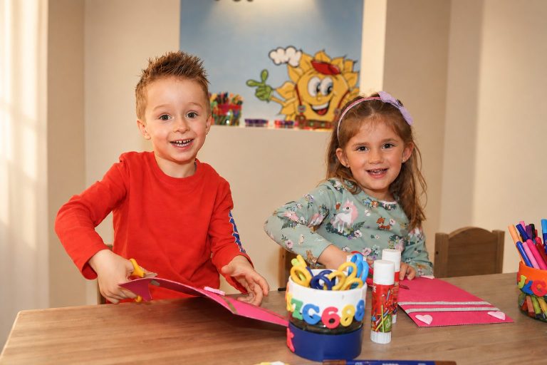 Two children doing crafts with paper and pens at a table in the craft corner of Hotel DreiSonnen in Serfaus