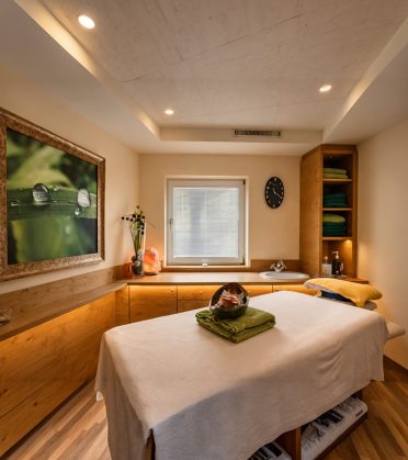 Behandlungsraum mit zwei Massageliegen, gedämpftes Licht und bereitgelegte Handtücher.
