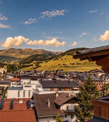View from a terrace over the rooftops of Serfaus to the wooded mountains.