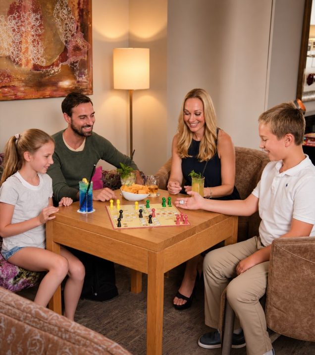 A family plays a board game together at a wooden table in the Hotel DreiSonnen.