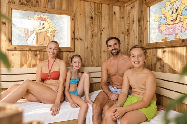 Familie mit zwei Kindern sitzt gemeinsam in der Familiensauna im Hotel DreiSonnen.