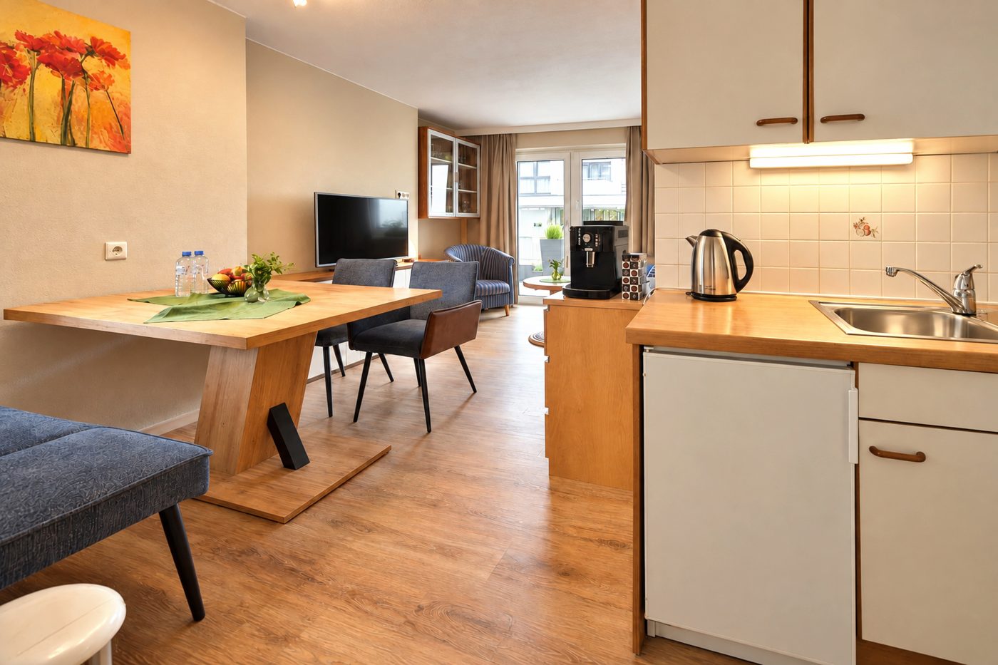 Kitchenette with kettle and sink, dining table and living area with TV in Apartment Anneliese at Hotel DreiSonnen in Serfaus