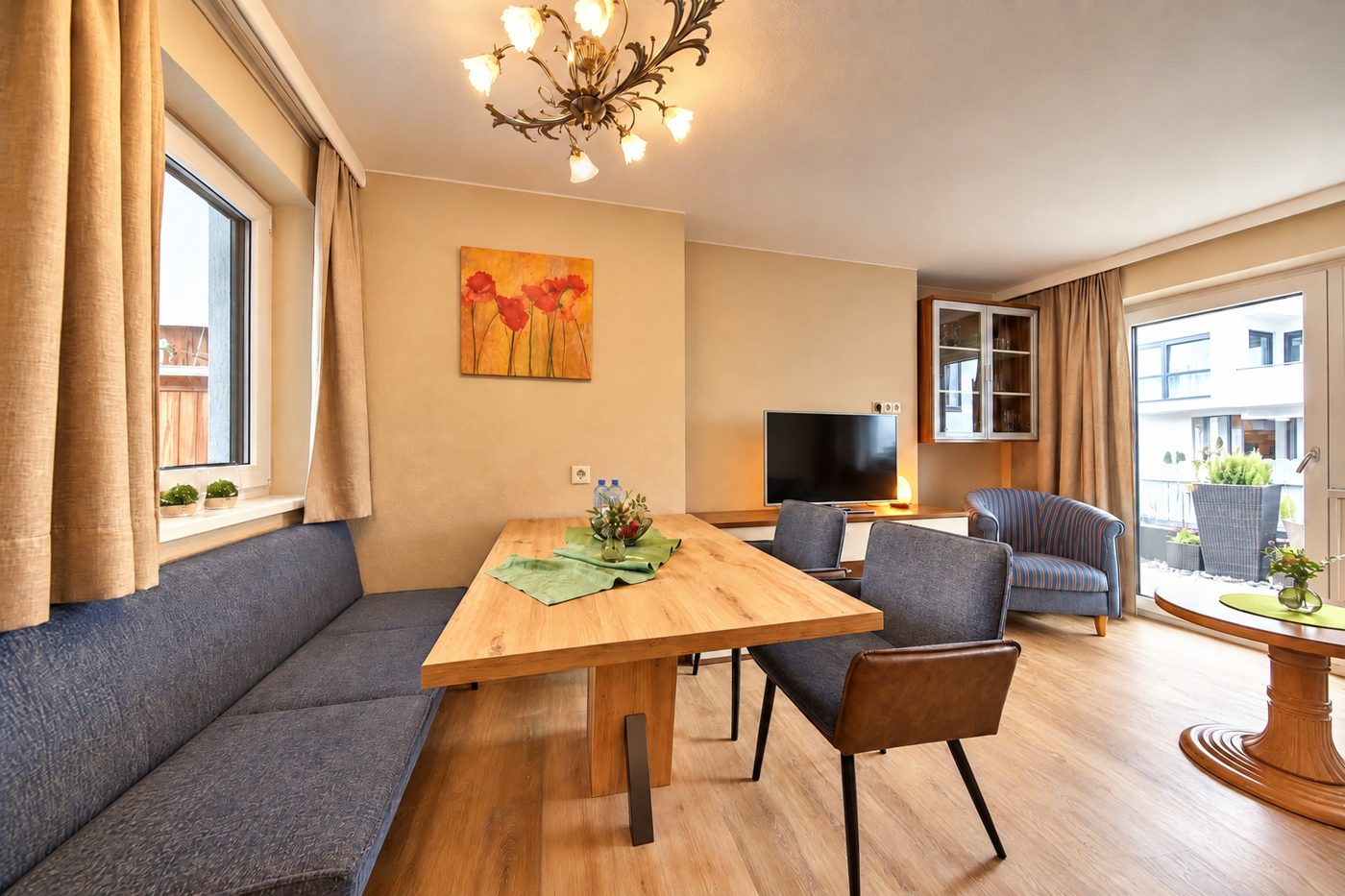 Dining area with corner bench, wooden table and chairs beneath the chandelier in Apartment Anneliese at Hotel DreiSonnen in Serfaus
