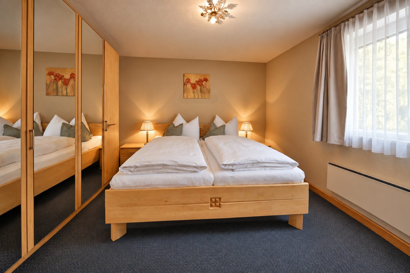 Bedroom with wooden double bed and a wardrobe with mirrored doors in the Apartment Anneliese at Hotel DreiSonnen in Serfaus