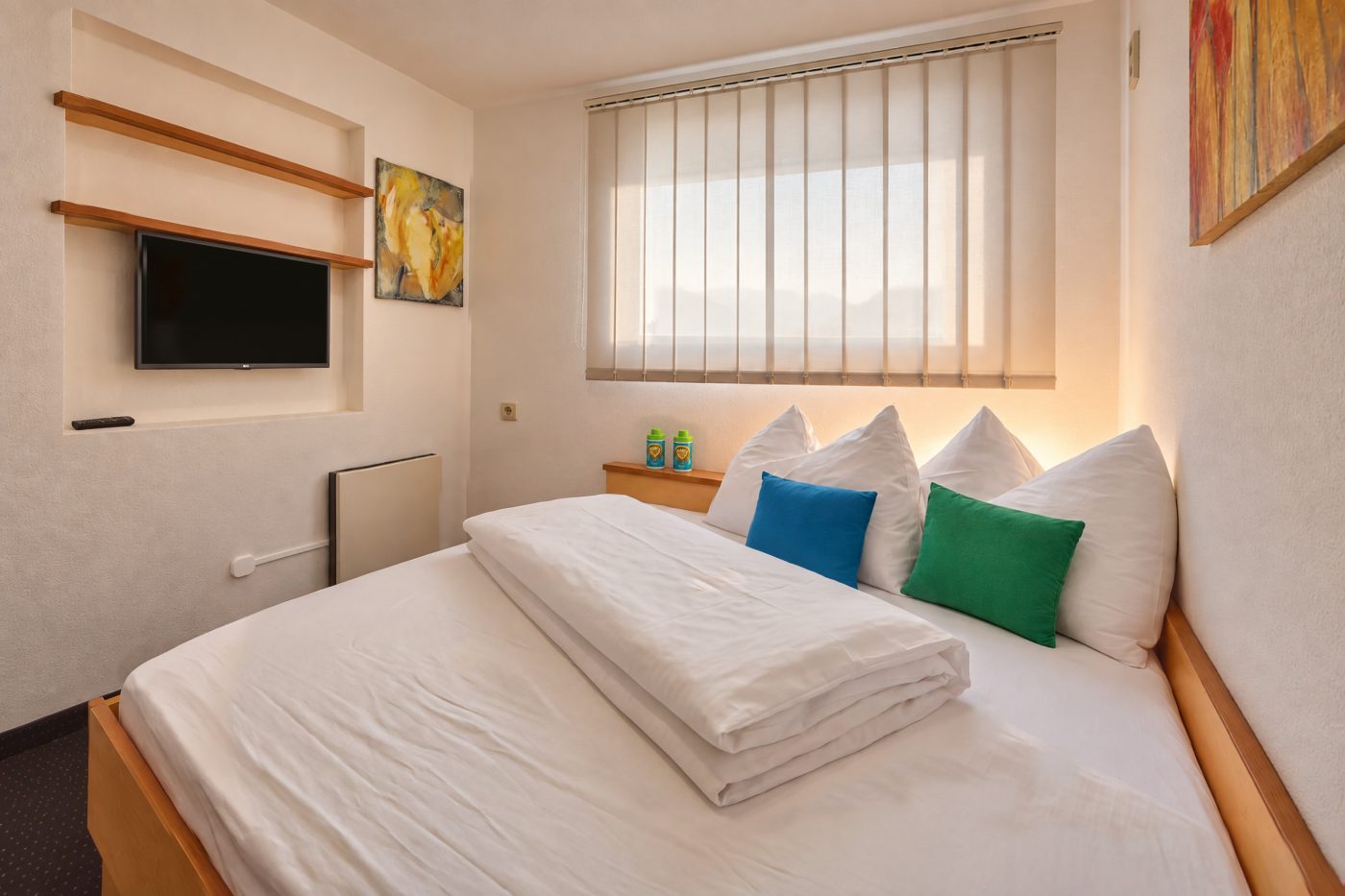 Second bedroom with single bed, colourful cushions and TV in Apartment Anneliese at Hotel DreiSonnen in Serfaus