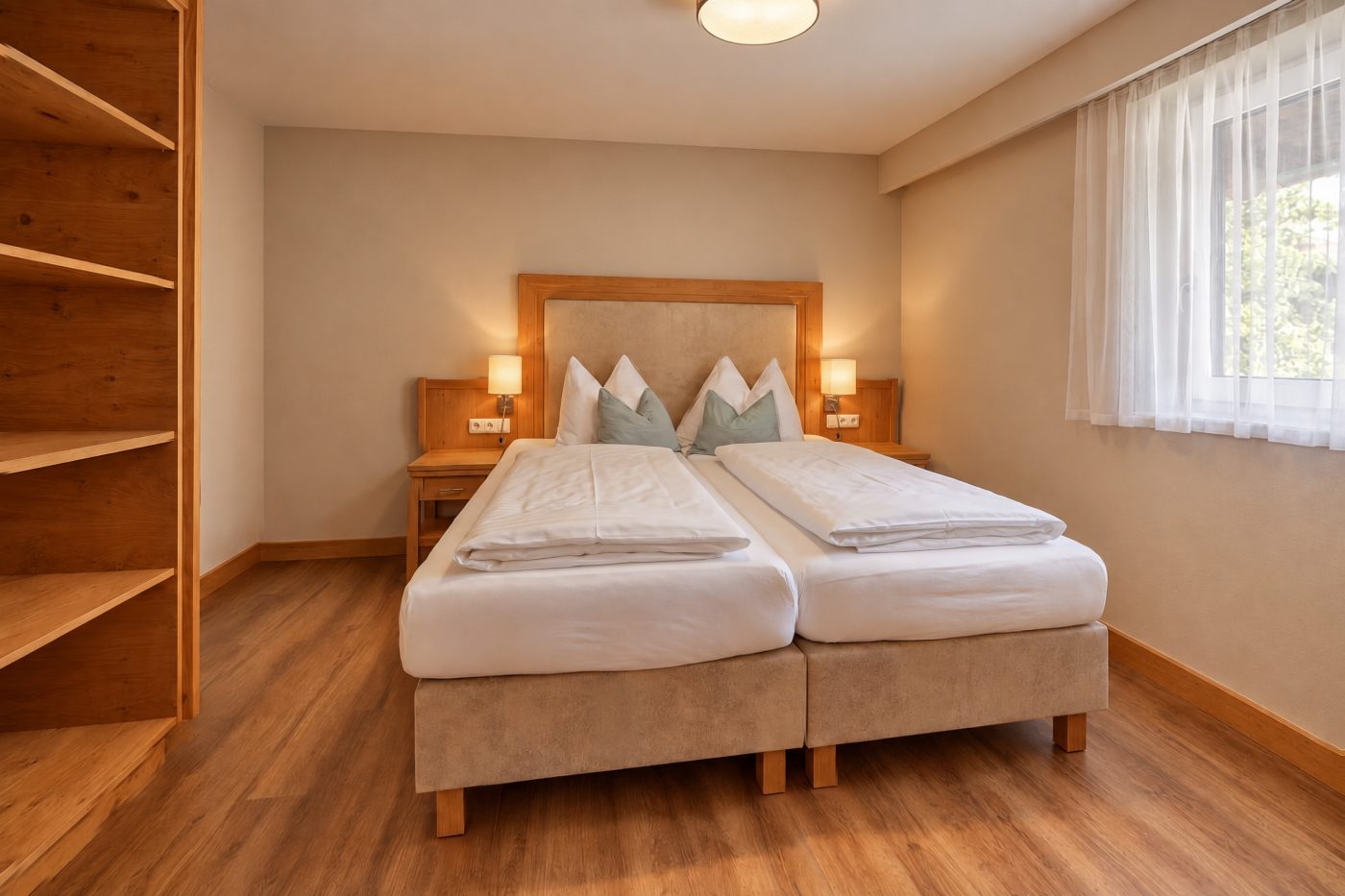 Schlafzimmer mit Doppelbett, gepolstertem Kopfteil und offenem Regal in der Ferienwohnung Irene des Hotels DreiSonnen in Serfaus