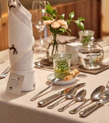 Festlich gedeckte Tafel mit gefalteter Serviette, Blumen und Besteck.