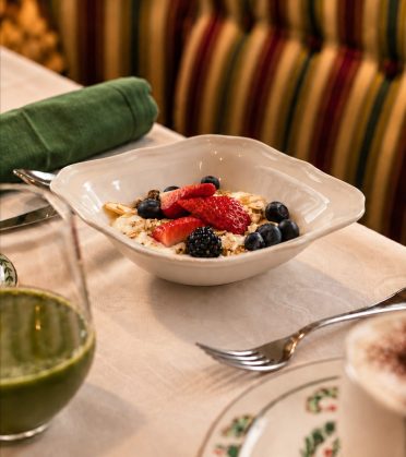 Bowl of muesli with strawberries, blueberries and blackberries on a laid breakfast table at Hotel DreiSonnen.