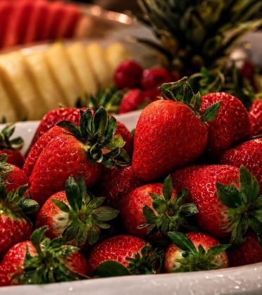 Platte mit Erdbeeren, dahinter Ananas und Melone, am Frühstücksbuffet des Hotel DreiSonnen in Serfaus