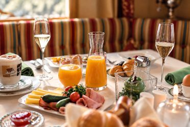 Gedeckter Frühstückstisch mit Saft, Aufschnitt und Gebäck
