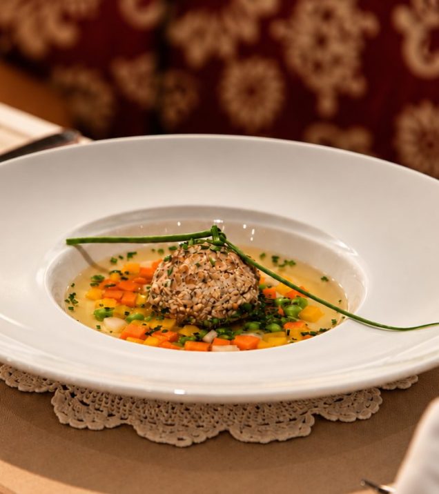Suppe mit Knödel auf weißem Teller am gedeckten Tisch im Hotel DreiSonnen.