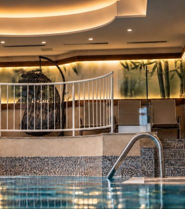 Hängesessel und Liegen am Rand des Innenpools im Hotel DreiSonnen.