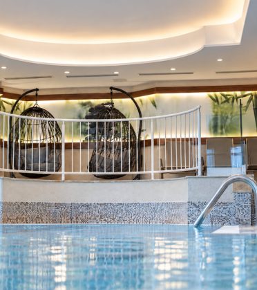 Innenpool mit Hängesesseln und Mosaikwand in der DreiSonnen Wellnesswelt in Serfaus.
