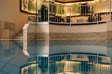Innenpool mit Sitzbereich hinter der Glasbrüstung im Hotel DreiSonnen in Serfaus