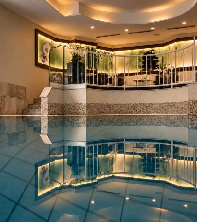 Innenpool mit Sitzbereich hinter der Glasbrüstung im Hotel DreiSonnen in Serfaus