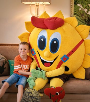 Junge mit dem Maskottchen Sonni auf dem Sofa in Sonnis Kids Club.