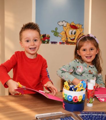 Two children making things with paper and pens at a table in Sonnis Kids Club at Hotel DreiSonnen in Serfaus