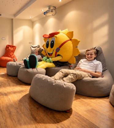 Kind mit dem Maskottchen Sonni auf Sitzsäcken im Kinderkino.