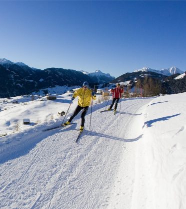Eine Langläuferin zieht ihre Spur über die sonnige Hochebene.
