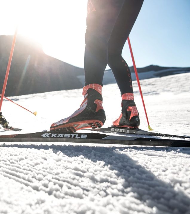 Nahaufnahme von Langlaufschuh und Ski auf der gespurten Loipe, im Gegenlicht der Wintersonne.