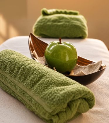 Massageliege mit Handtuch, grünem Apfel und Kerzen im Hotel DreiSonnen in Serfaus