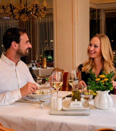 Paar beim Abendessen mit Weißwein im Speisesaal des Hotel DreiSonnen in Serfaus