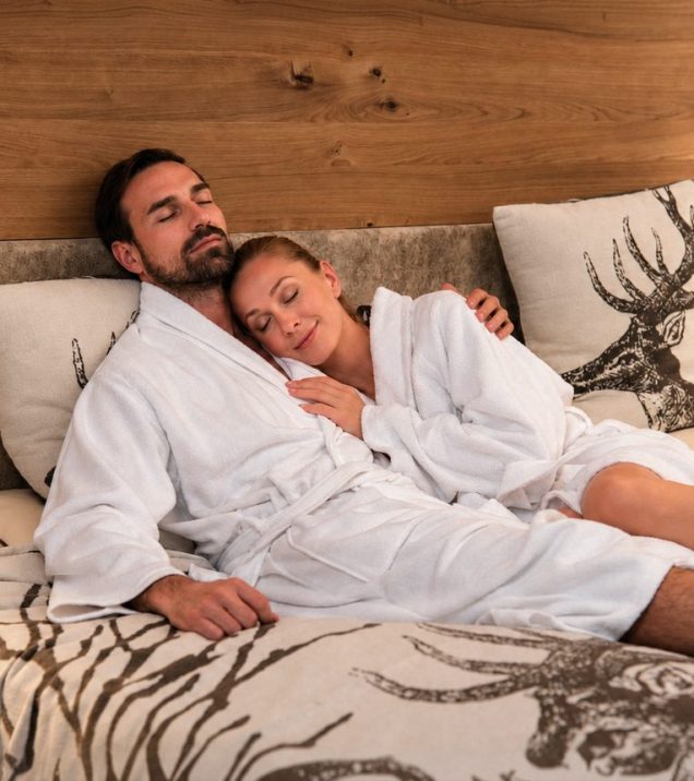 A couple in bathrobes lying relaxed on the bed at Hotel DreiSonnen in Serfaus