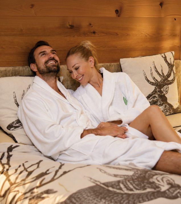 A couple in bathrobes relaxing side by side on the heated waterbed in the quiet room of Hotel DreiSonnen in Serfaus.