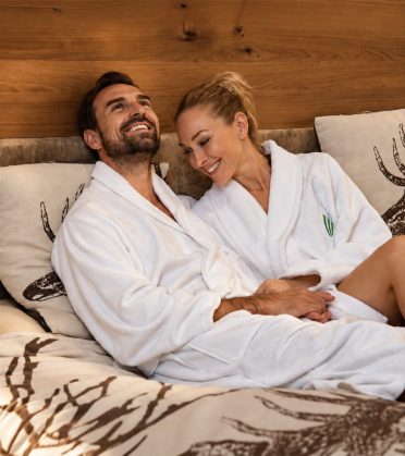 Paar im Bademantel liegt nebeneinander auf dem Wasserbett.