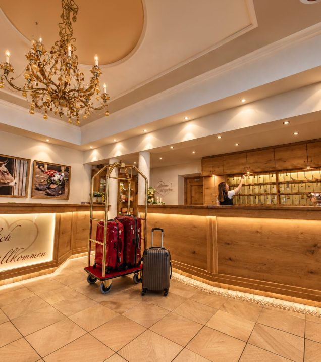 Reception of Hotel DreiSonnen in Serfaus with a luggage trolley and bags in front of the front desk.
