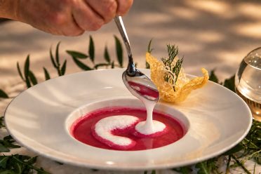 Rote-Bete-Suppe wird am Tisch verfeinert, daneben steht ein Käsechip.