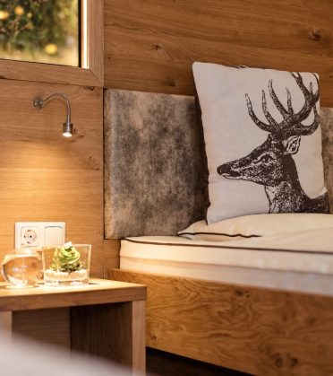 A quiet corner with a wooden bench, deer cushions and a wall lamp.