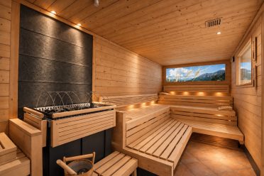 Sauna mit Steinwand und beleuchtetem Panoramabild