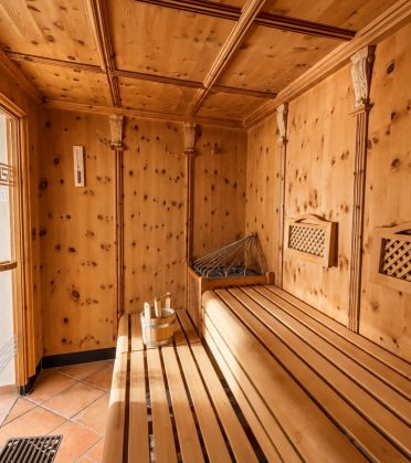 Inside the Swiss stone pine sauna with wooden benches at Hotel DreiSonnen in Serfaus.
