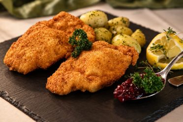 Schnitzel mit Petersilienkartoffeln und Preiselbeeren auf einer Schieferplatte