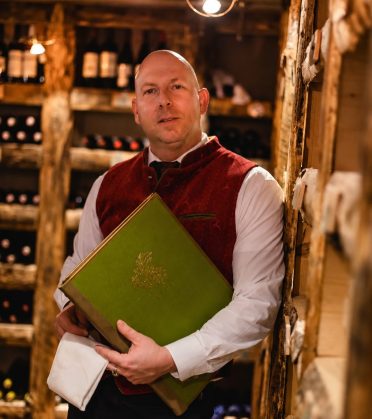 Sommelier Milos with the wine list in the wine cellar of Hotel DreiSonnen in Serfaus.