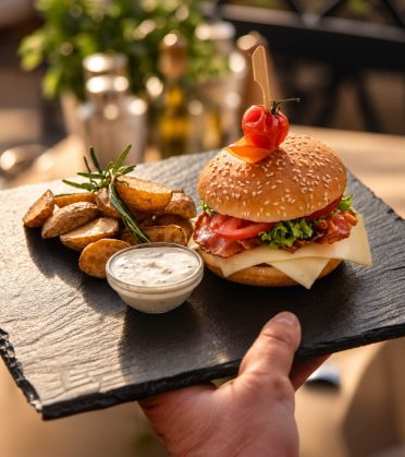 Sonniburger mit Kartoffelspalten und Dip auf einer Schieferplatte im Hotel DreiSonnen in Serfaus.