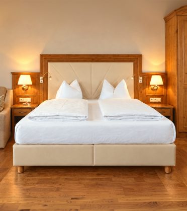 Deluxe-Doppelzimmer Angela im Hotel DreiSonnen in Serfaus mit Doppelbett, Sofa und Sitzecke am Fenster