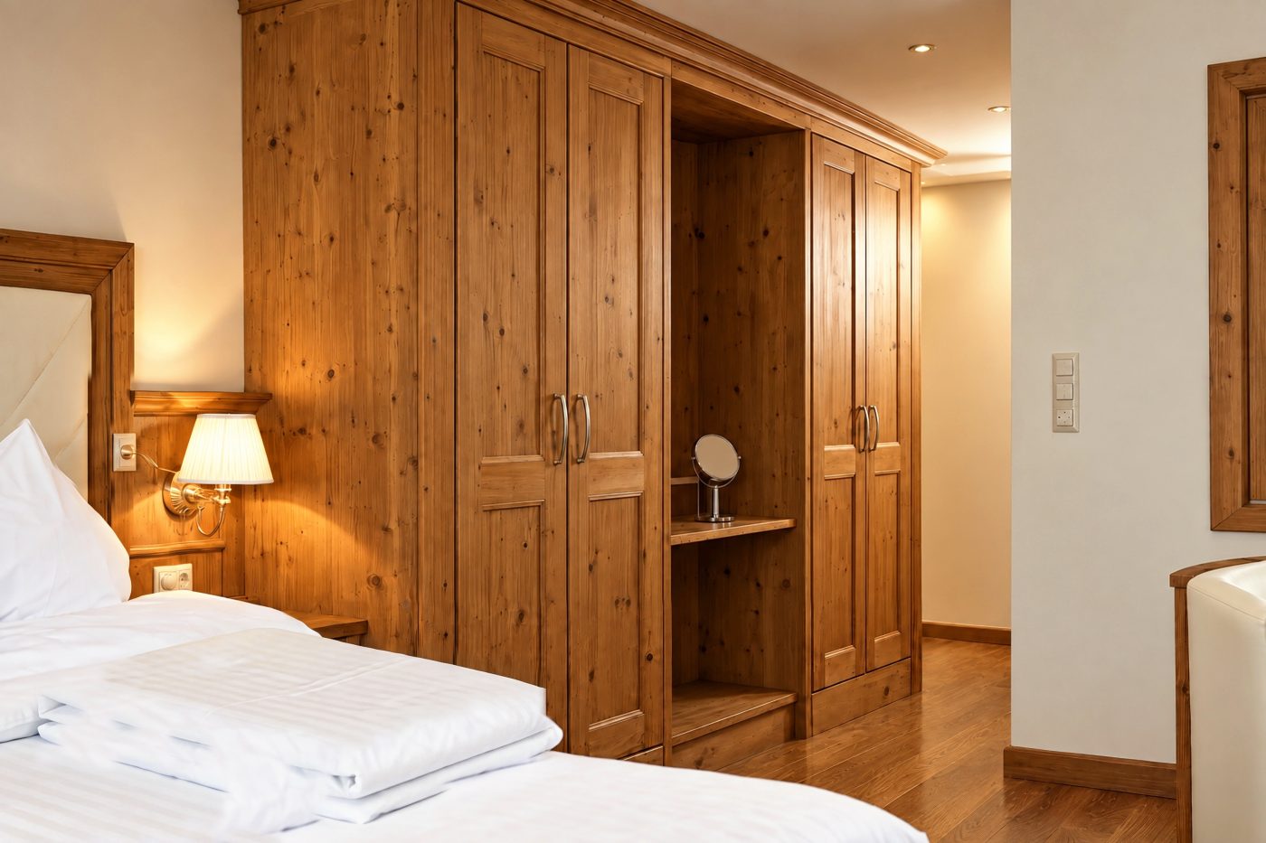 Kleiderschrank aus Holz mit offenem Fach und Kosmetikspiegel im Zimmer Angela des Hotels DreiSonnen in Serfaus