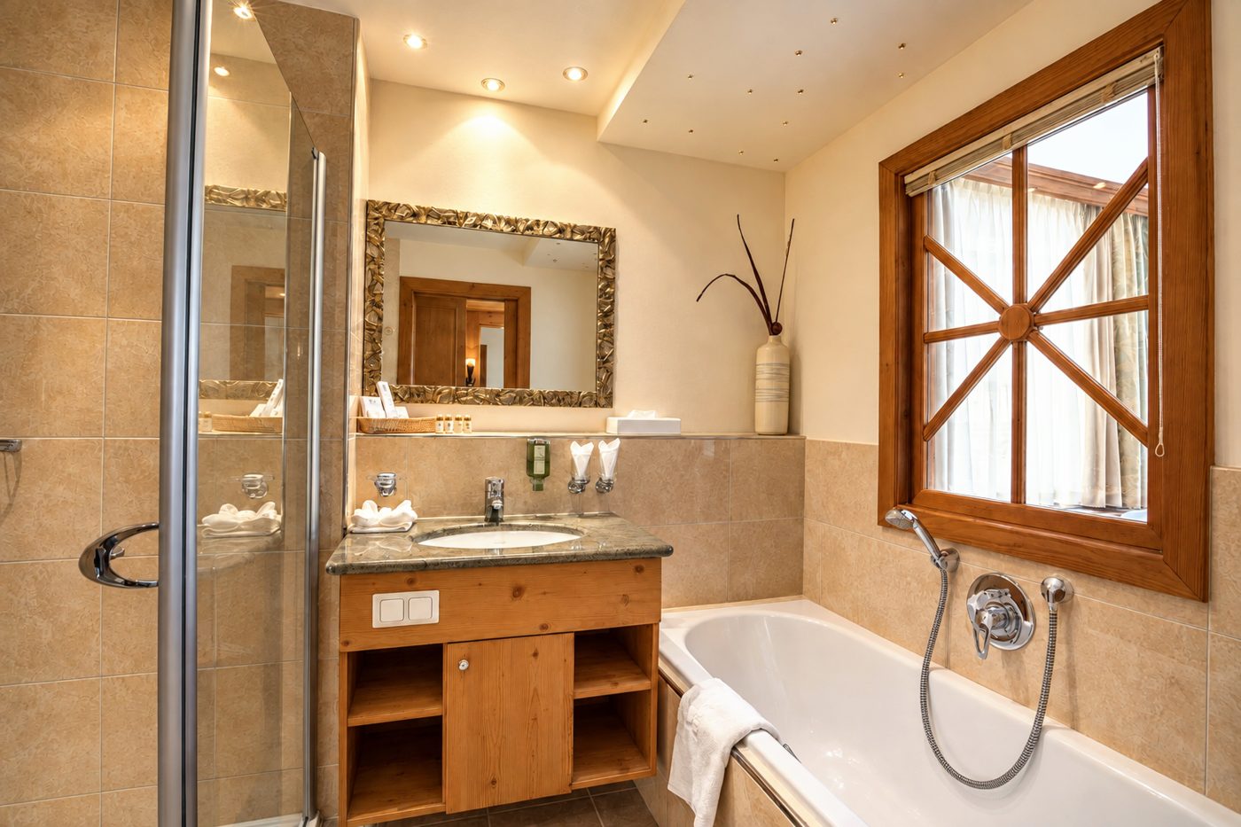 Badezimmer im Zimmer Angela des Hotels DreiSonnen in Serfaus mit Waschtisch, Badewanne, Dusche und Fenster
