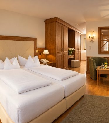 Vergleichbare Deluxe-Suite vom Typ des Zimmers Elias im Hotel DreiSonnen in Serfaus mit Doppelbett, Sofa und Sitzecke am Fenster