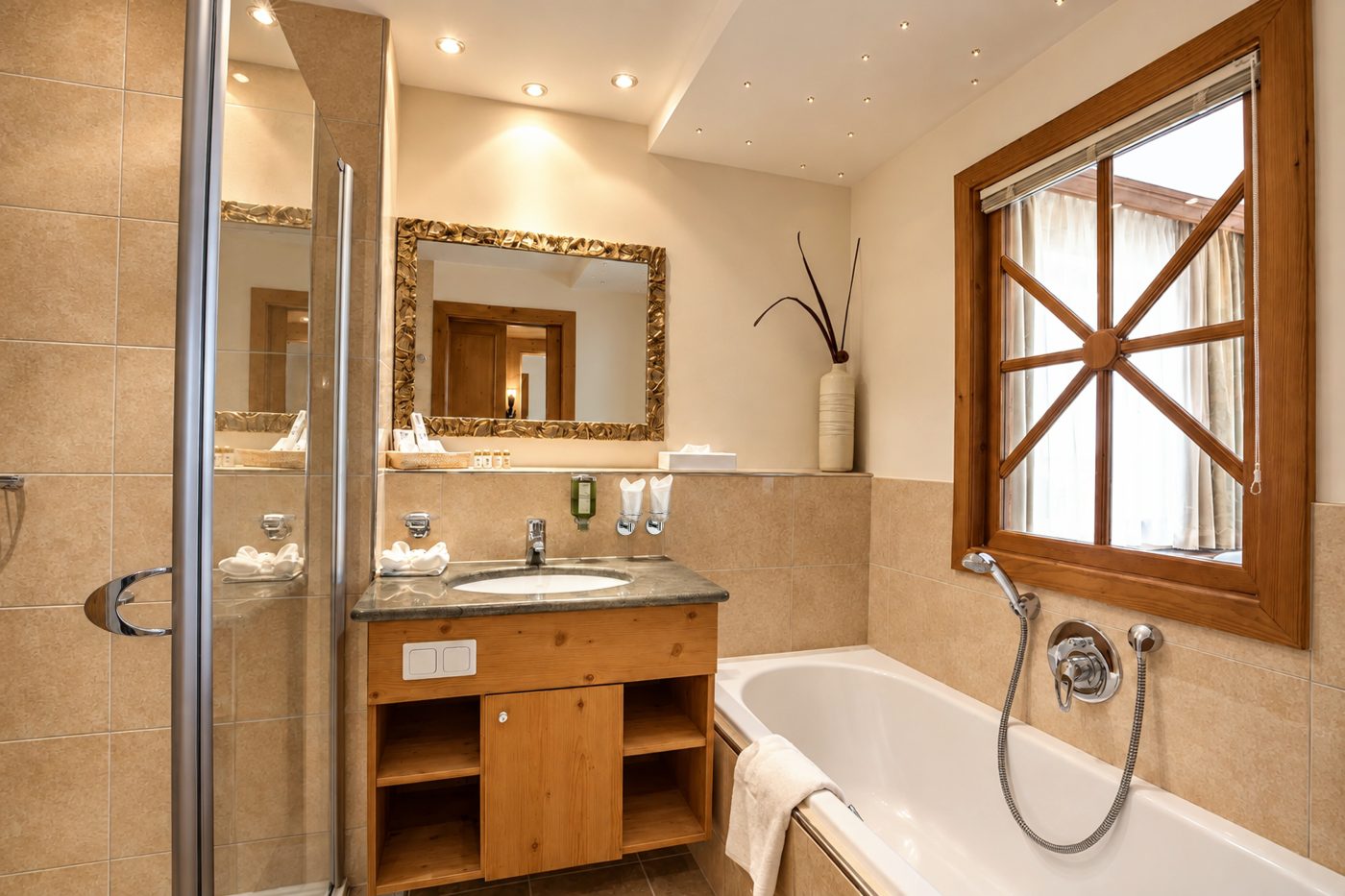 Badezimmer im Zimmer Elias des Hotels DreiSonnen in Serfaus mit Waschtisch, Badewanne, Dusche und Sprossenfenster