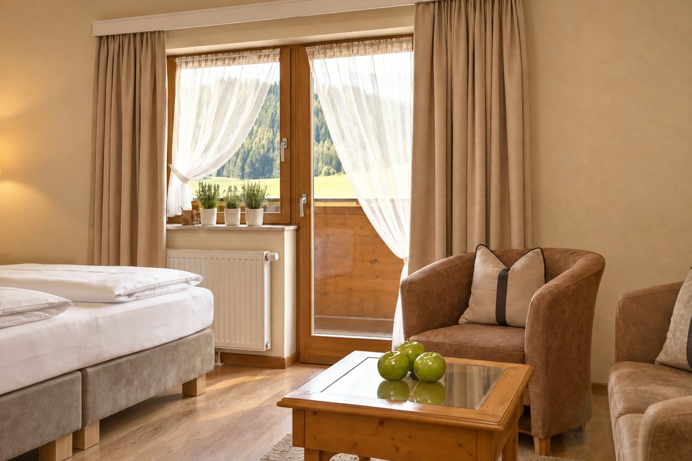 Sessel und Couchtisch vor der Balkontür mit Blick auf Wald und Wiesen in einem vergleichbaren Zimmer vom Typ der Suite Elisabeth im Hotel DreiSonnen in Serfaus