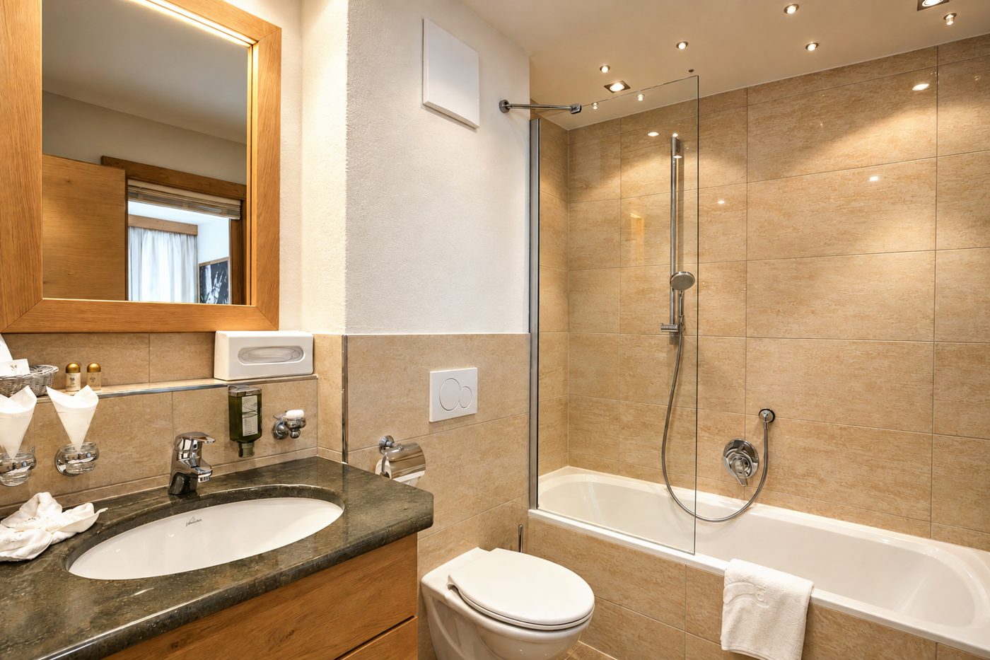 Bathroom in the Florian room at Hotel DreiSonnen in Serfaus with vanity unit, mirror and bathtub with shower screen