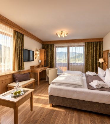 Familienzimmer Kaiser Franzl im Hotel DreiSonnen in Serfaus mit Bett, Sitzbank, Schreibtisch und Balkontür
