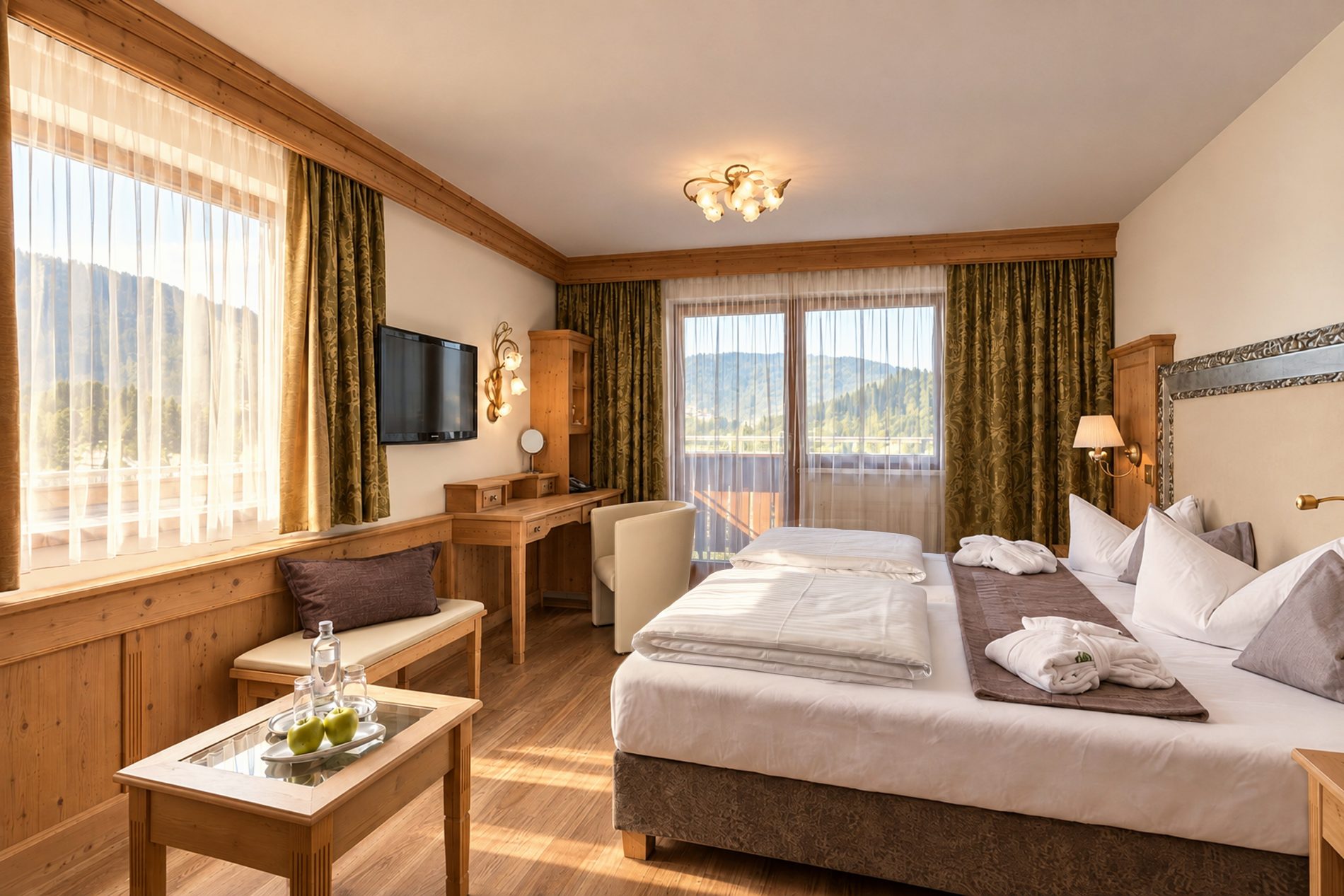 Bed, bench, desk and balcony door with mountain views in the Family Room Kaiser Franzl at Hotel DreiSonnen in Serfaus