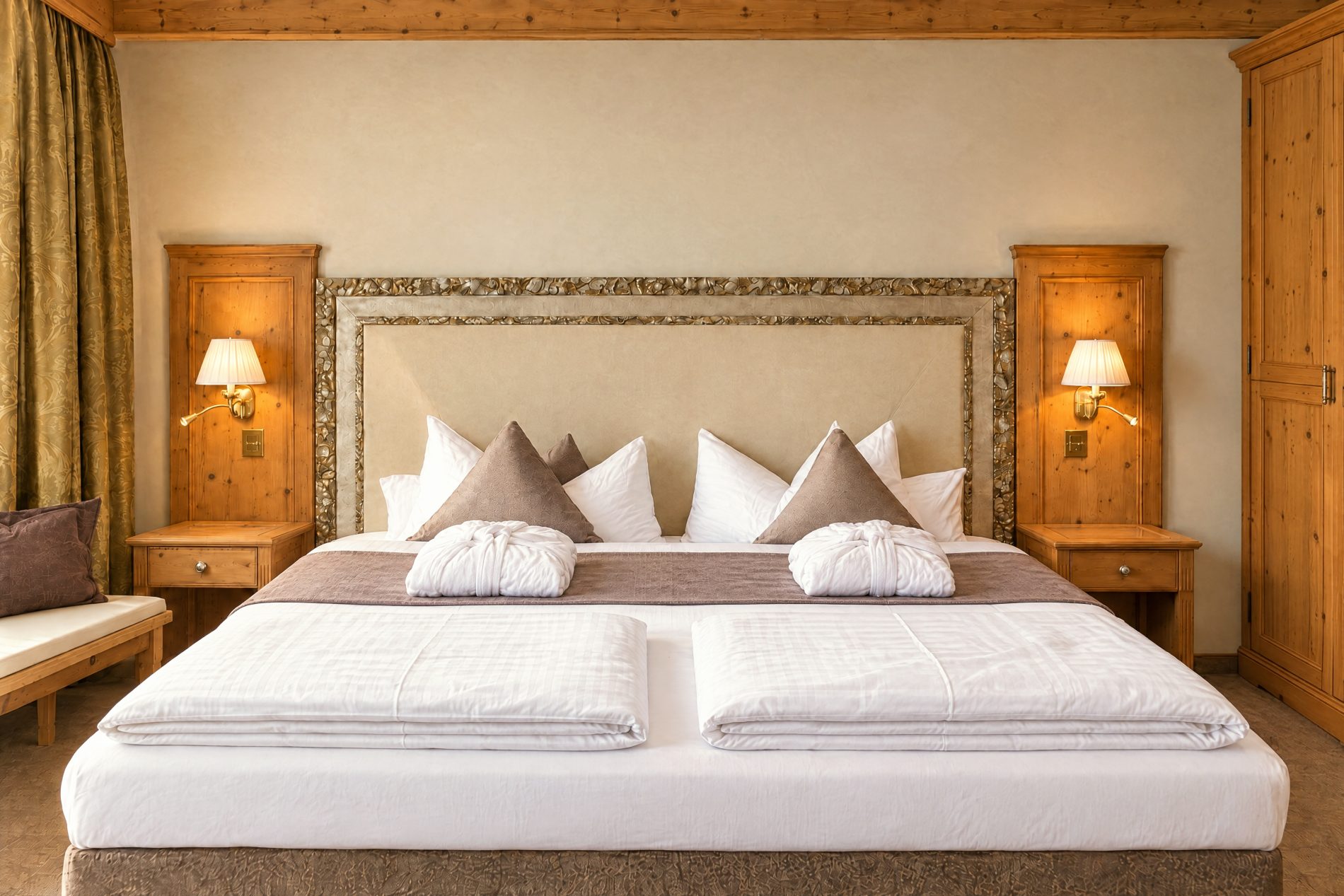 Double bed with upholstered headboard, bathrobes and bedside lamps in the Kaiser Franzl room at Hotel DreiSonnen in Serfaus