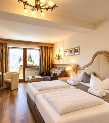 Deluxe-Doppelzimmer Kaiserin Sissi im Hotel DreiSonnen in Serfaus mit geschwungenem Kopfteil, Kronleuchter und Balkontür