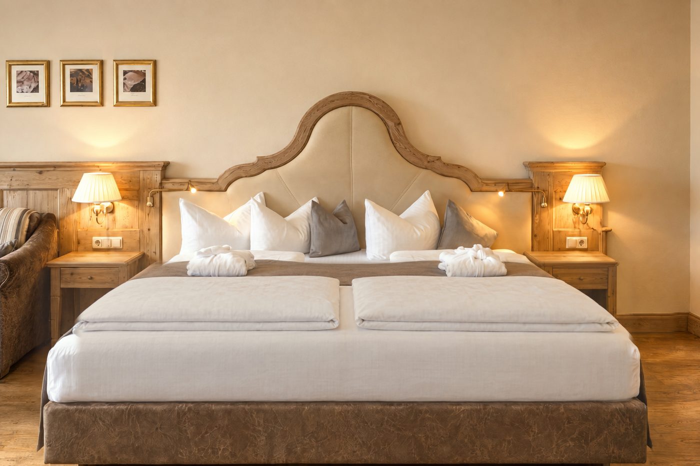 Doppelbett mit geschwungenem Kopfteil aus Altholz, Nachttischen und Wandleuchten im Zimmer Kaiserin Sissi des Hotels DreiSonnen in Serfaus