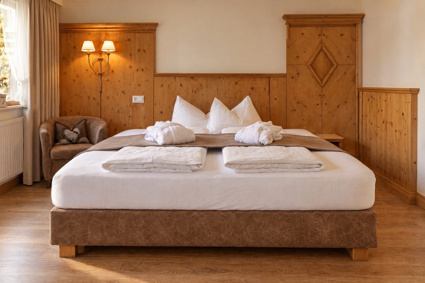 Doppelbett vor der Holzvertäfelung mit Rautenmotiv und Wandleuchten im Zimmer König Ludwig des Hotels DreiSonnen in Serfaus